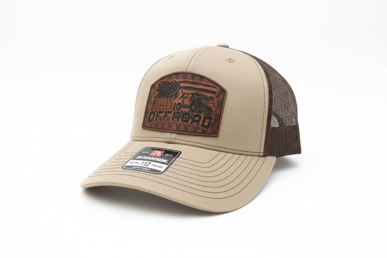 Khaki and chocolate‑brown trucker hat with a leather ‘Life Is Better Off Road’ patch on a white background, Hollarwood Outfitters
