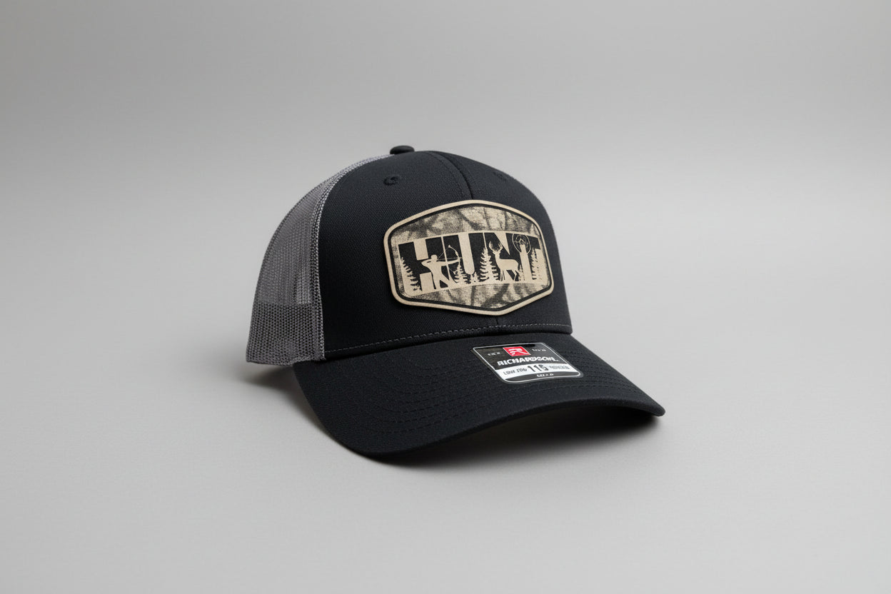 Trucker hat featuring a leatherette patch with a hunt‑scene design, Hollarwood Outfitters.