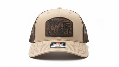 Khaki and chocolate‑brown trucker hat with a leather ‘Life Is Better Off Road’ patch on a white background, Hollarwood Outfitters.