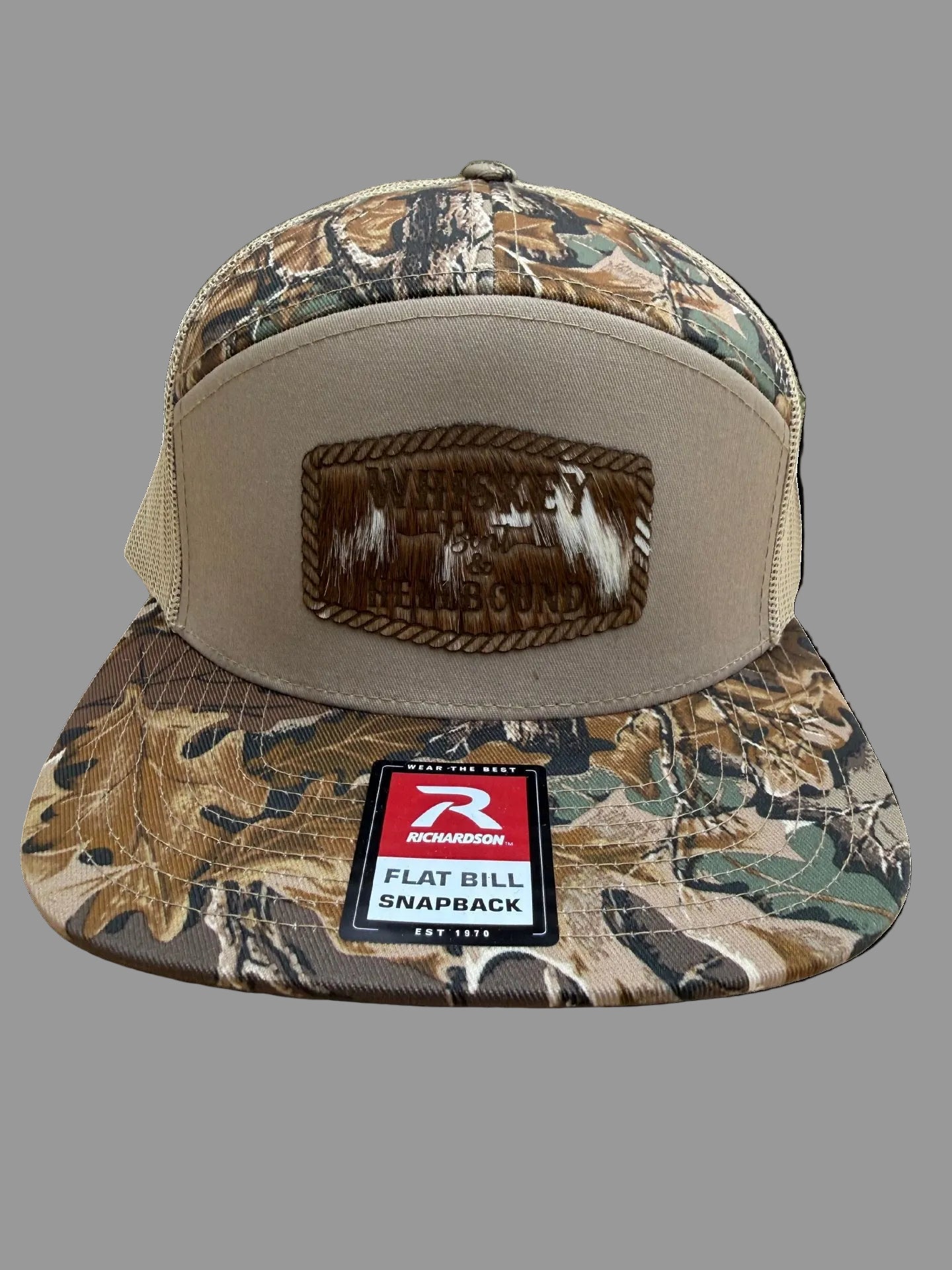 Camouflage flat bill hat featuring a leather Whiskey Bent Hellbound patch on a gray background, Hollarwood Outfitters